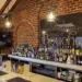 Brick-walled bar with wooden beams, a long white counter filled with assorted liquor bottles and a large Venue Bouchon sign on the brick wall behind.