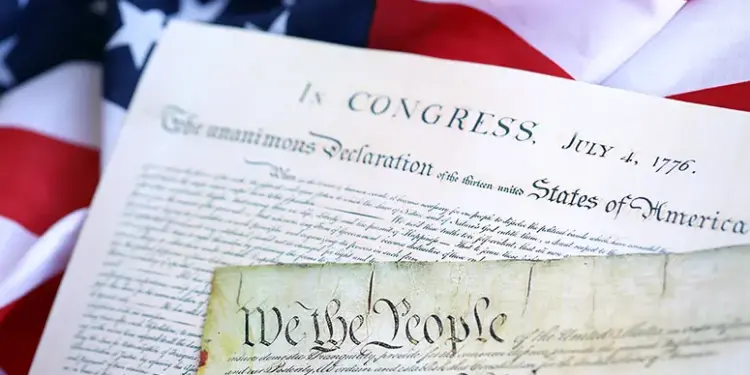 250th-westminster-reading-image - Carroll News | Carroll Publications | Carroll County, MD Close-up of the U.S. Declaration of Independence and a parchment reading 'We the People,' with an American flag in the background.
