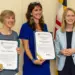 - Carroll News | Carroll Publications | Carroll County, MD Three women stand indoors, two in blue-toned dresses holding framed certificates and smiling as the third woman in a light blue blazer stands beside them.