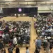 westminster-graduations - Carroll News | Carroll Publications | Carroll County, MD Large school gym packed with hundreds of attendees seated and facing a stage with screens on either side.