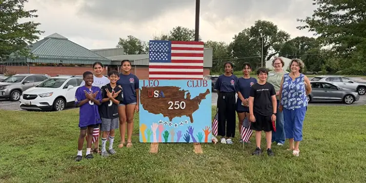 LeoPatriotism - Carroll News | Carroll Publications | Carroll County, MD Group of children and adults posing beside a handmade sign reading LEO Club USA 250, with an American flag overhead.