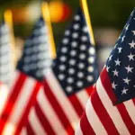 Rows of American flags on flagpoles, close-up foreground flag with others blurred in the background at a patriotic display