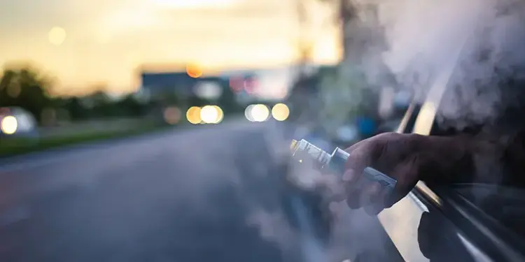 vape smoke_image - Carroll News | Carroll Publications | Carroll County, MD Person vaping from a car window at sunset, with vapor plume filling the air outside the vehicle.
